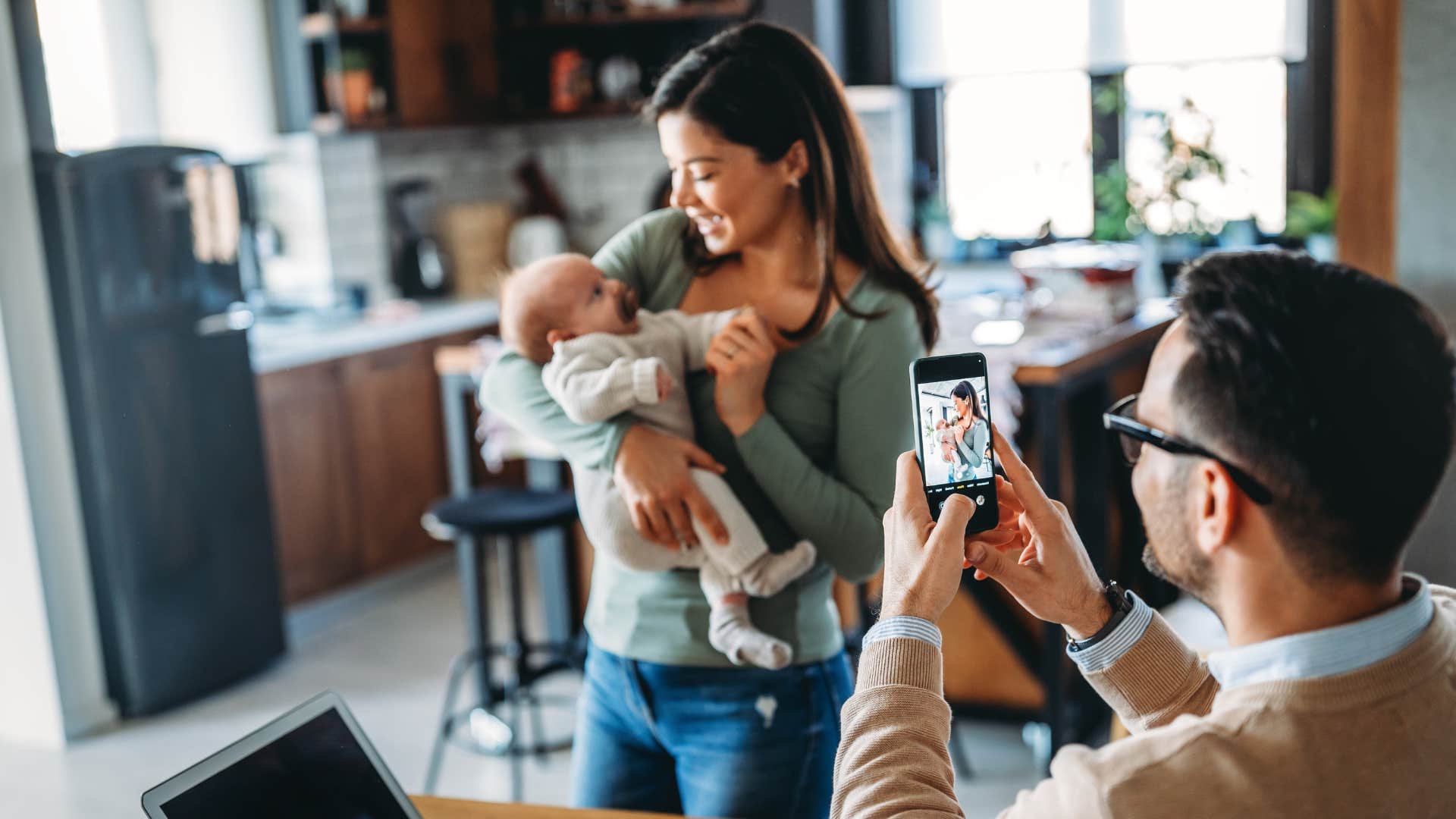 couple taking photo of newborn for social media