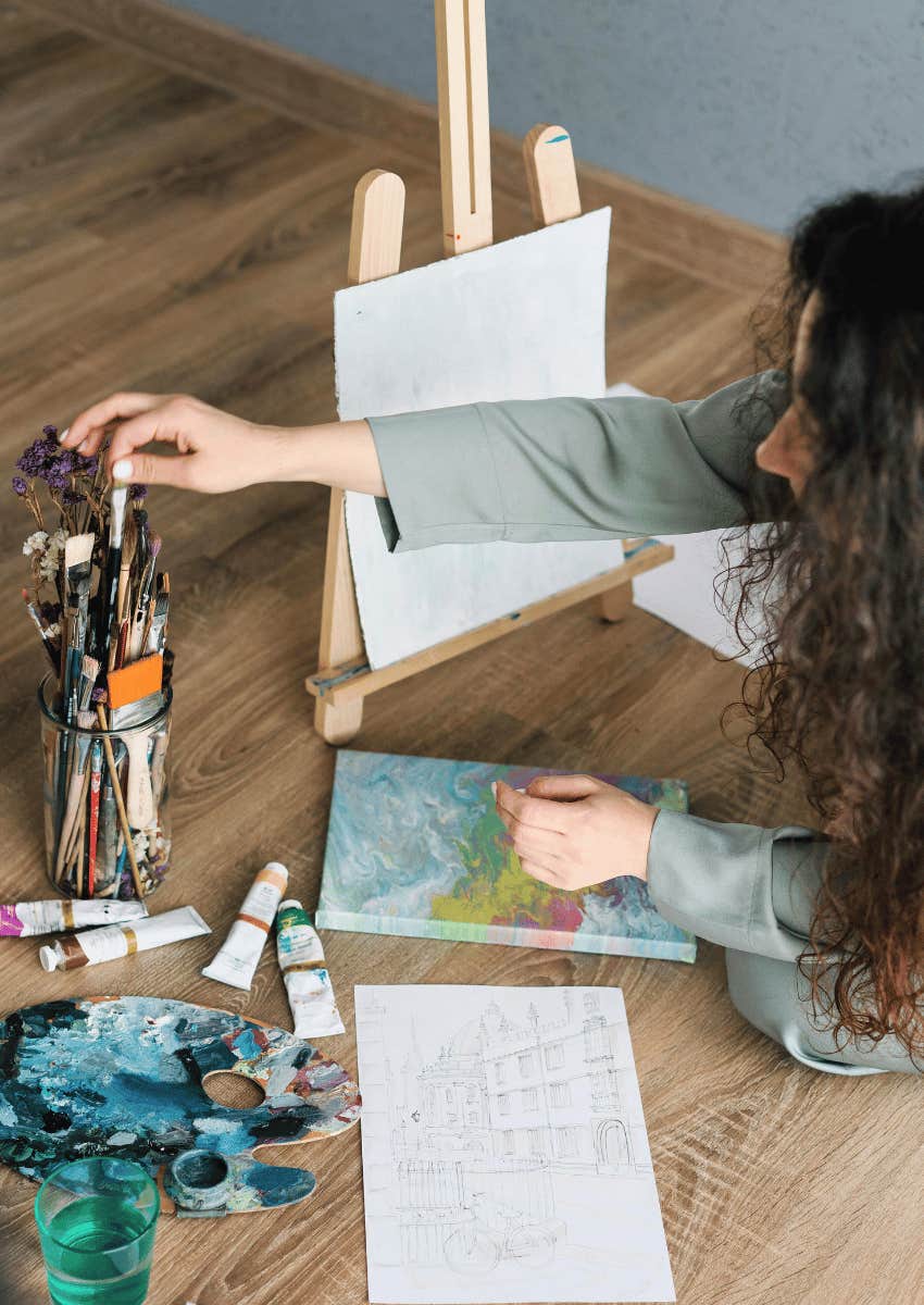 woman on ground painting on a small easle