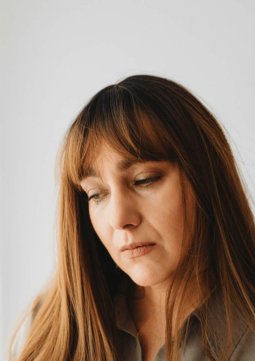 woman with a somber expression looking down