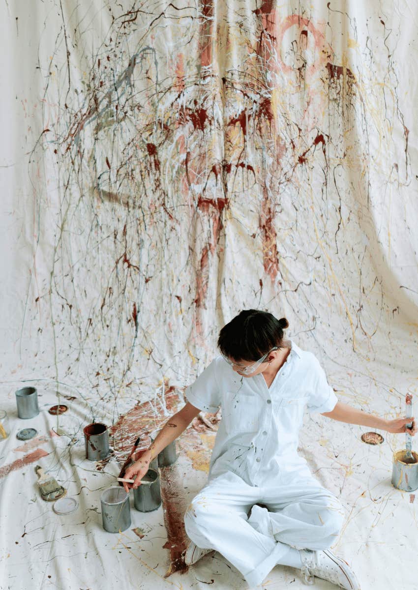 woman sitting on ground surrounded by messy art