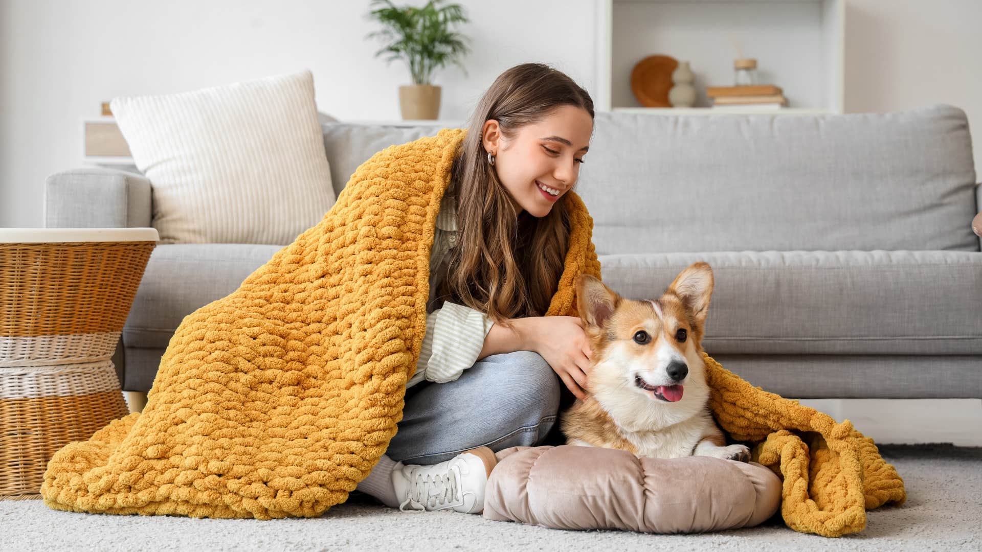 sentimental woman wrapped in blanket petting dog