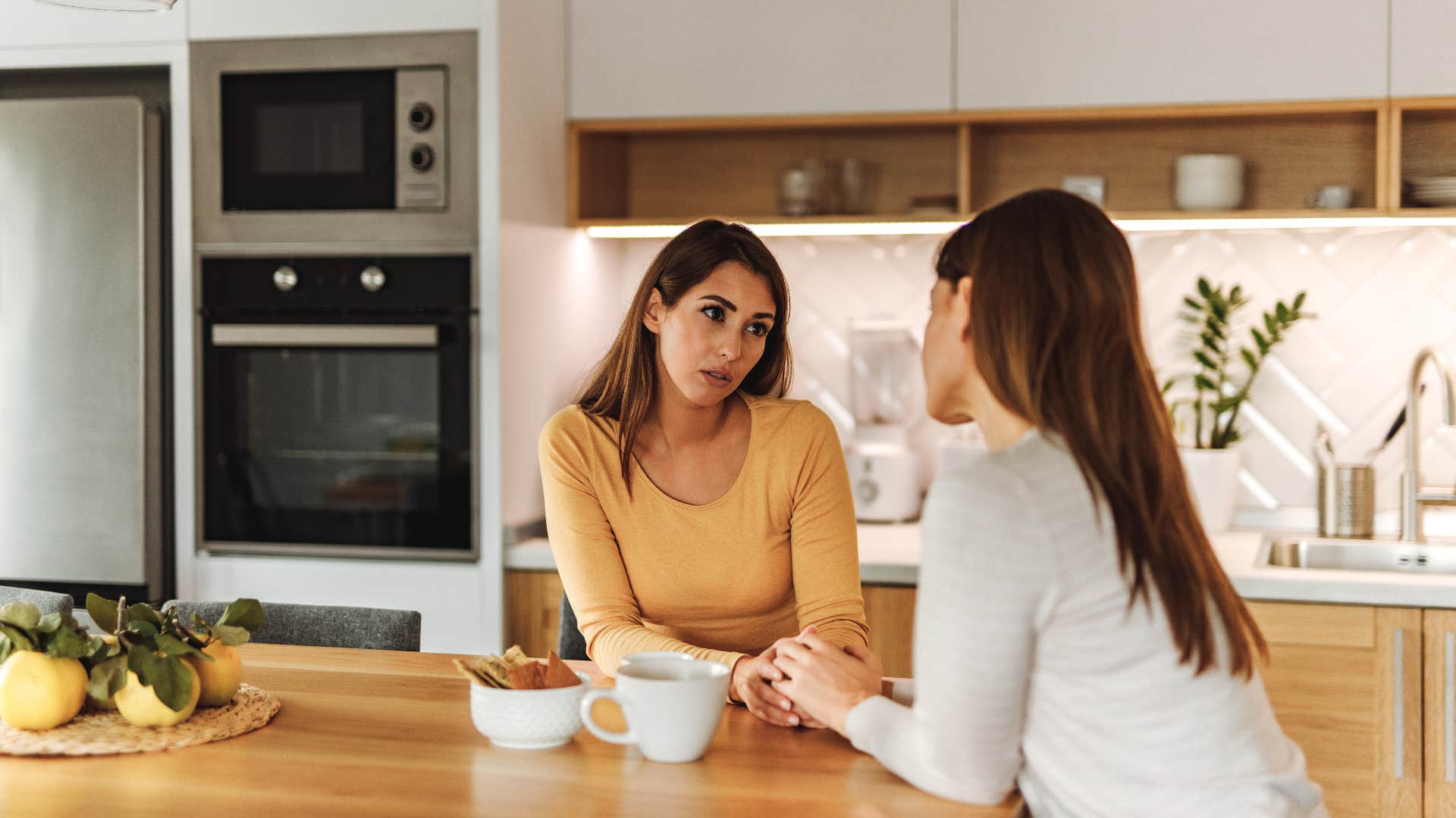 women having one on one conversation in kitchen