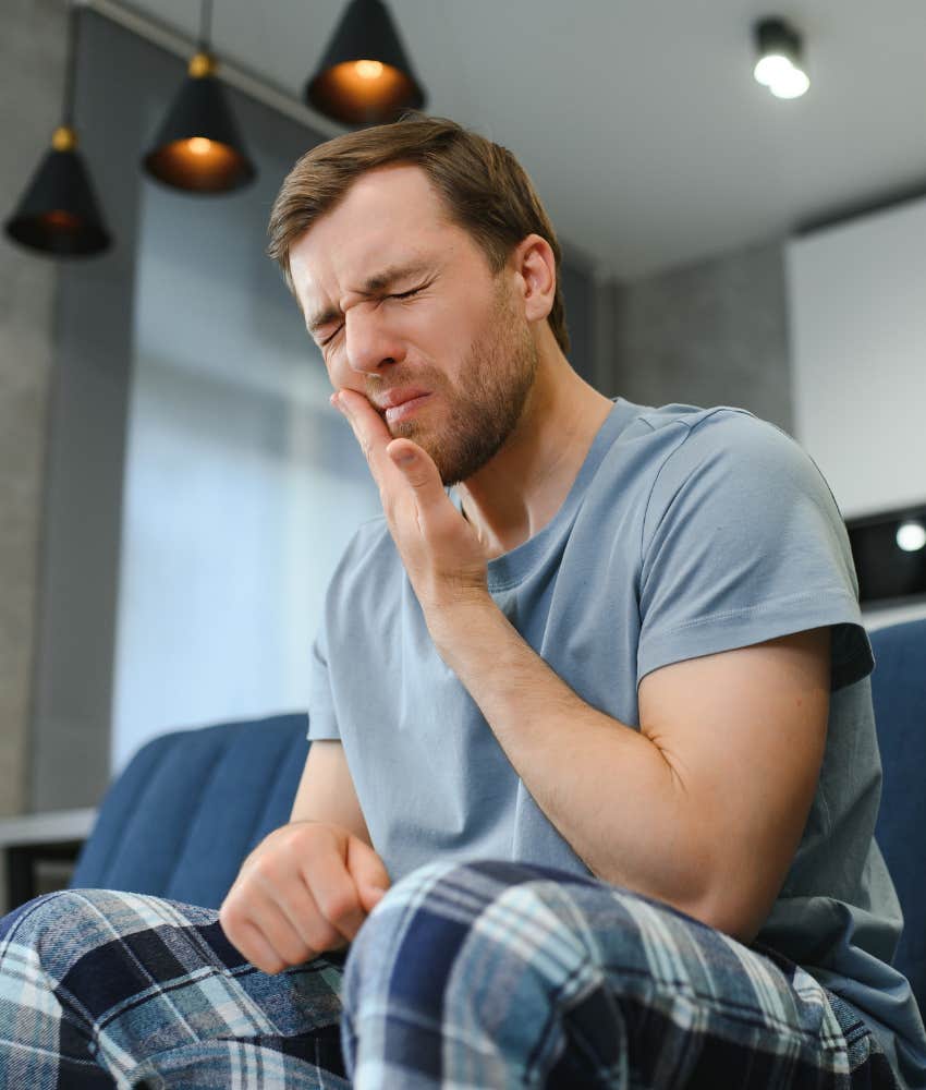Anguished person touches side of mouth showing obvious bad tooth fillingh