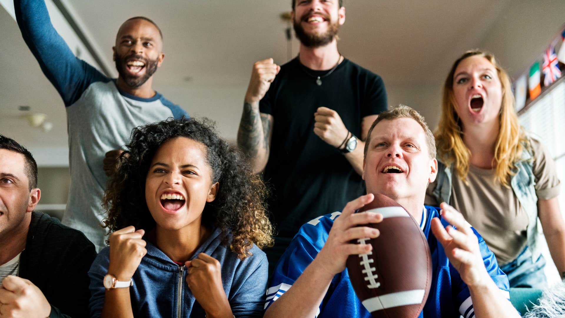 Excited group of friends watch football showing way to tell he loves you