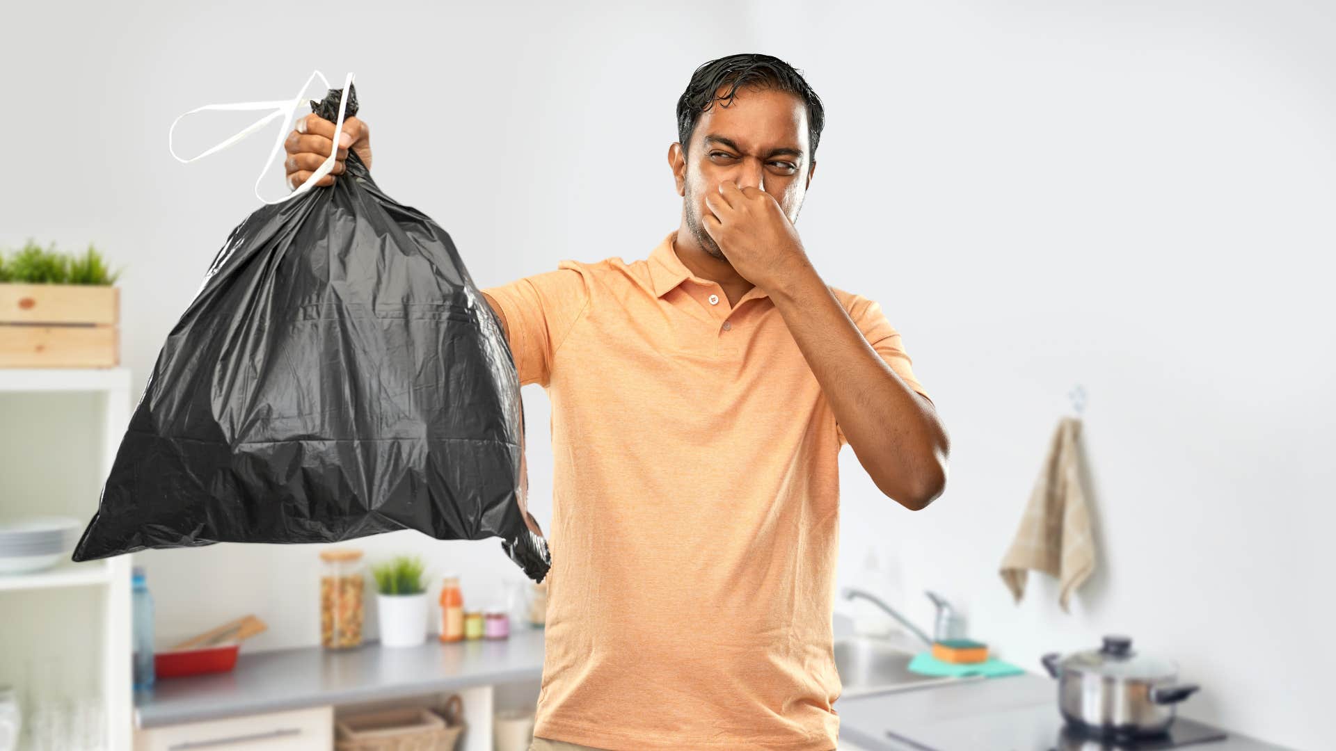 man holding up garbage bag upset at smell