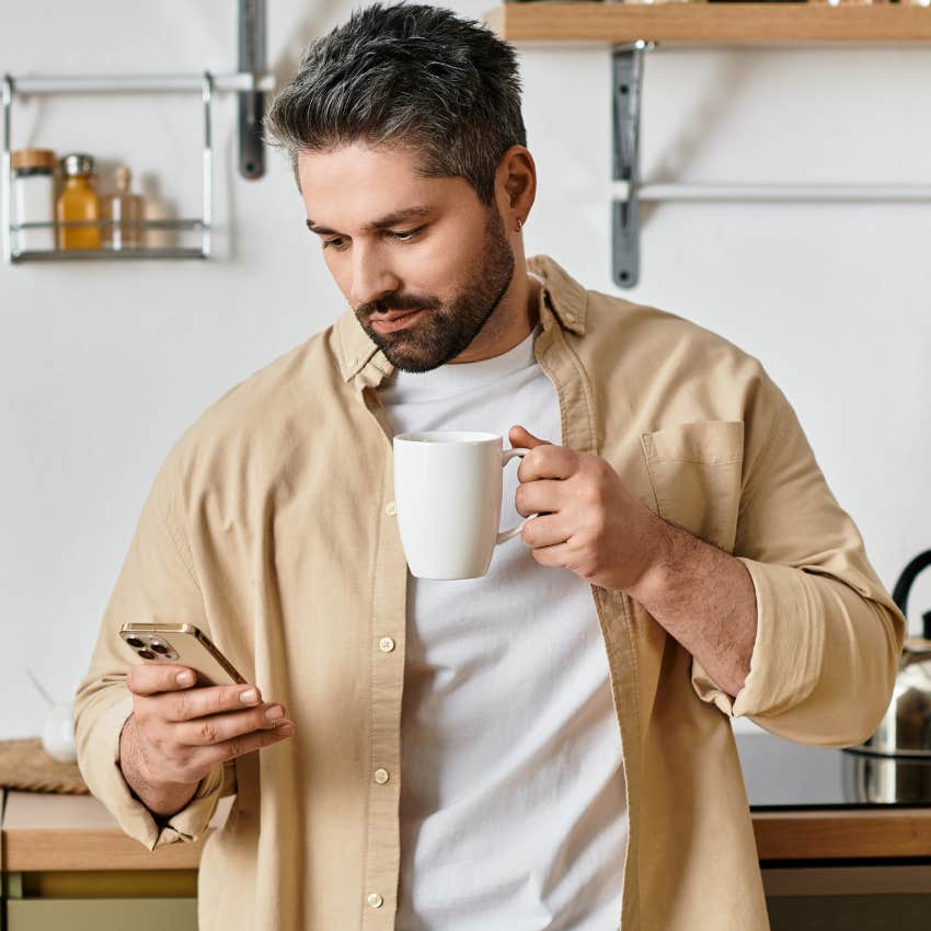 Man whose kitchen utensils are basic looking at his phone