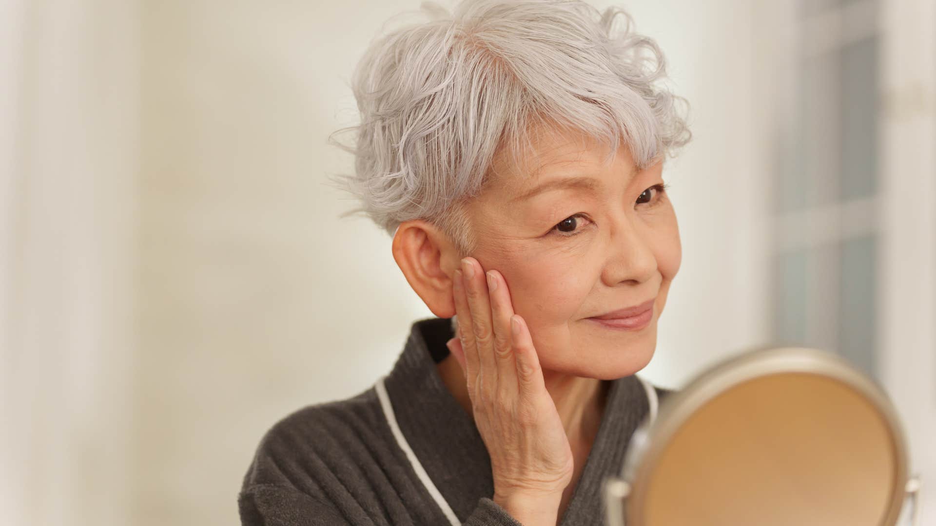 woman looking in mirror doing skincare routine