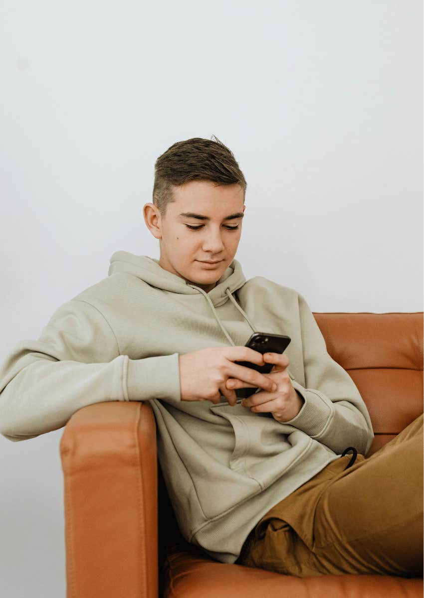 young man on couch looking down at his phone