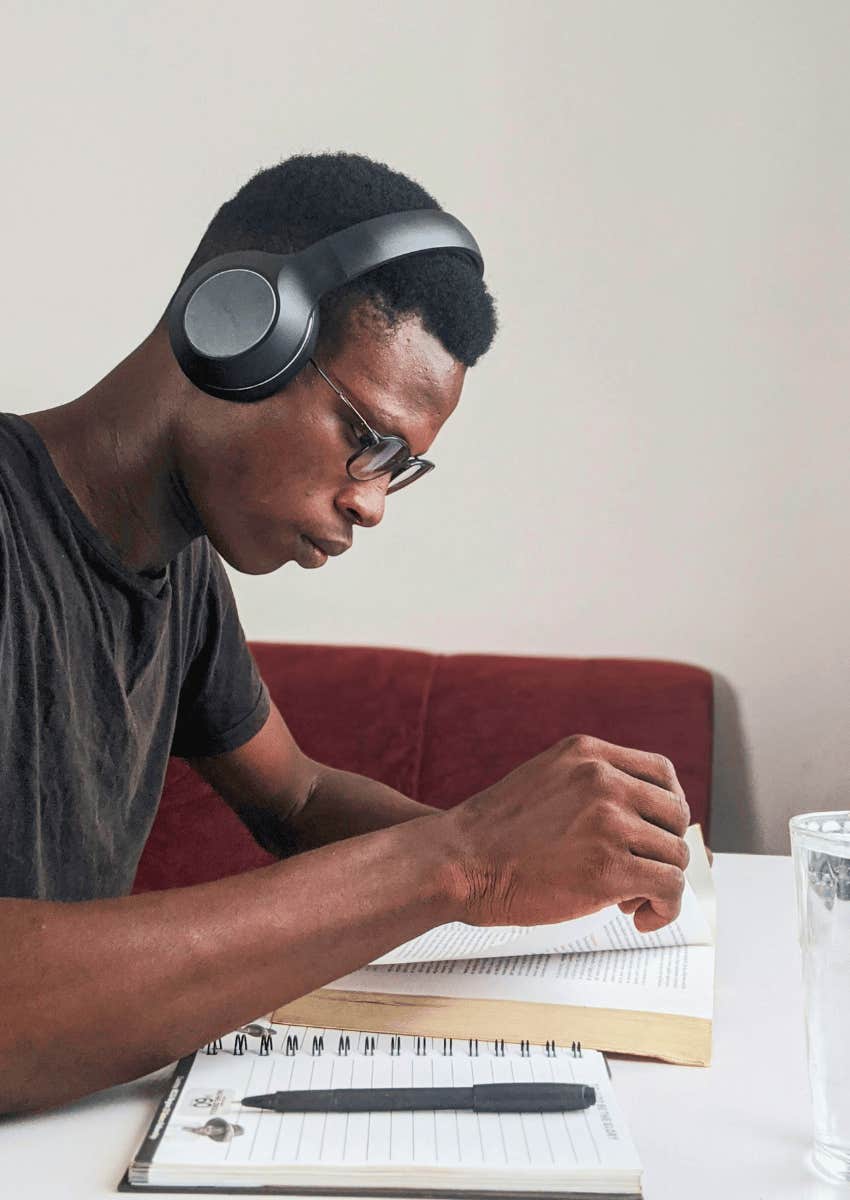 young man wearing headphones and focused on reading