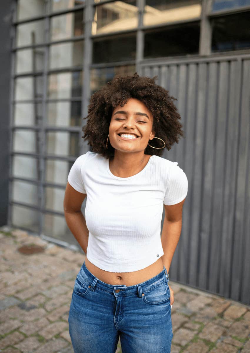 young woman in a crop top smiling widely