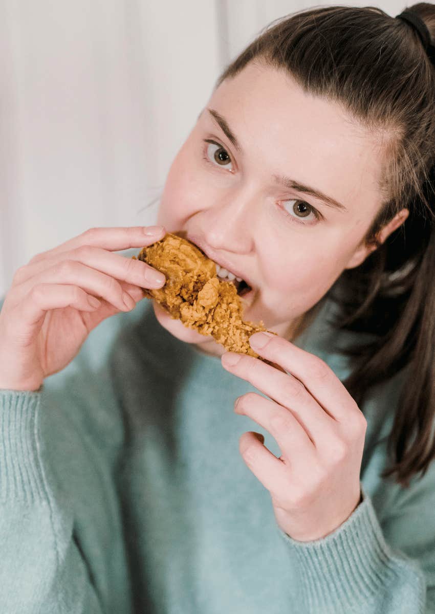 young woman enjoying fried chicken leg