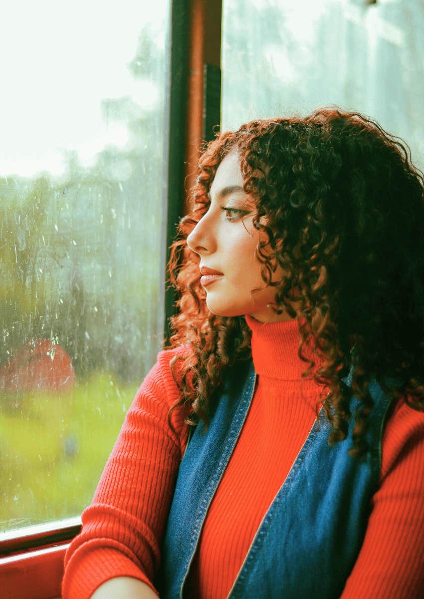 young woman looking out of rainy window