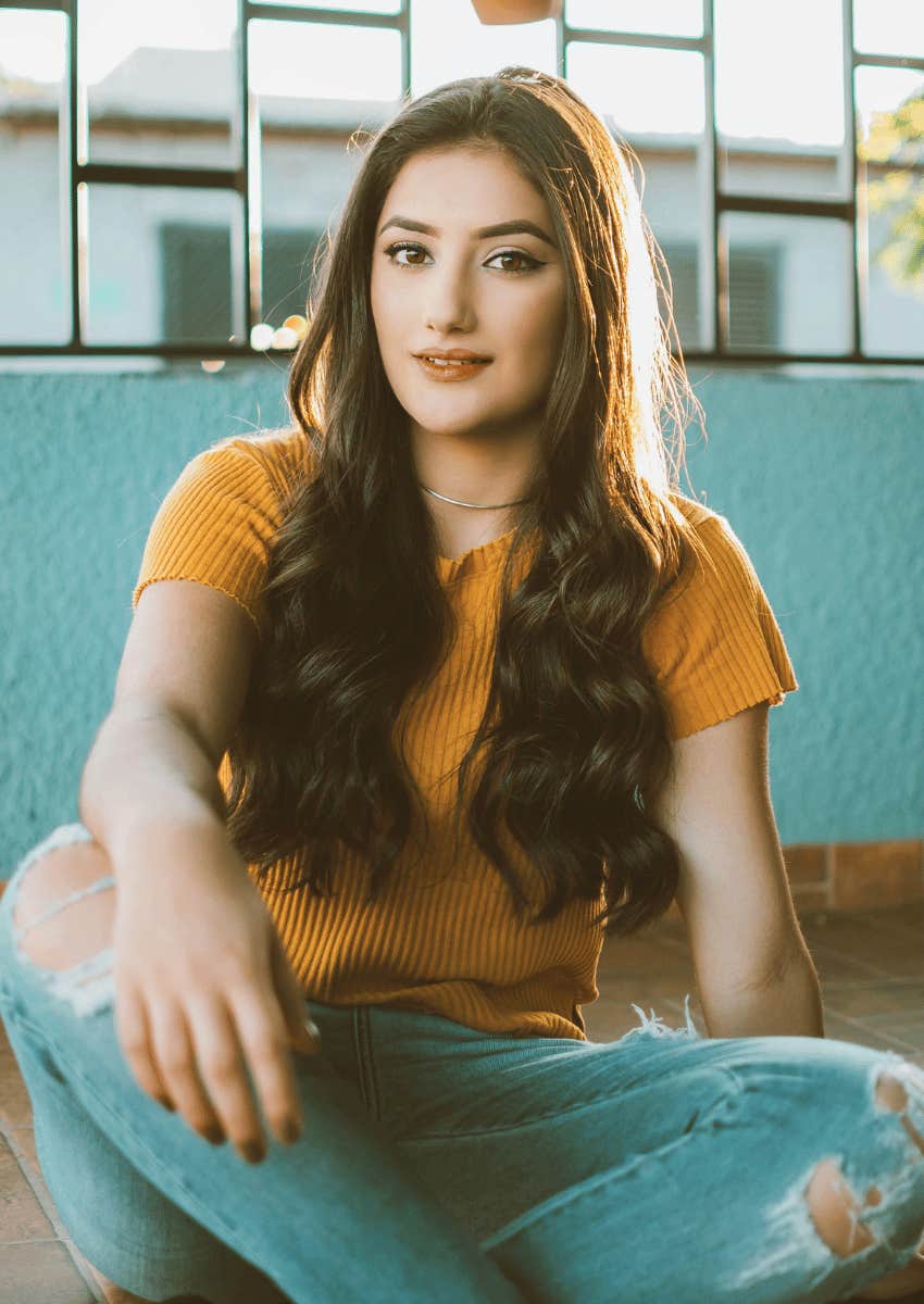young woman wearing ripped jeans and sitting on the ground