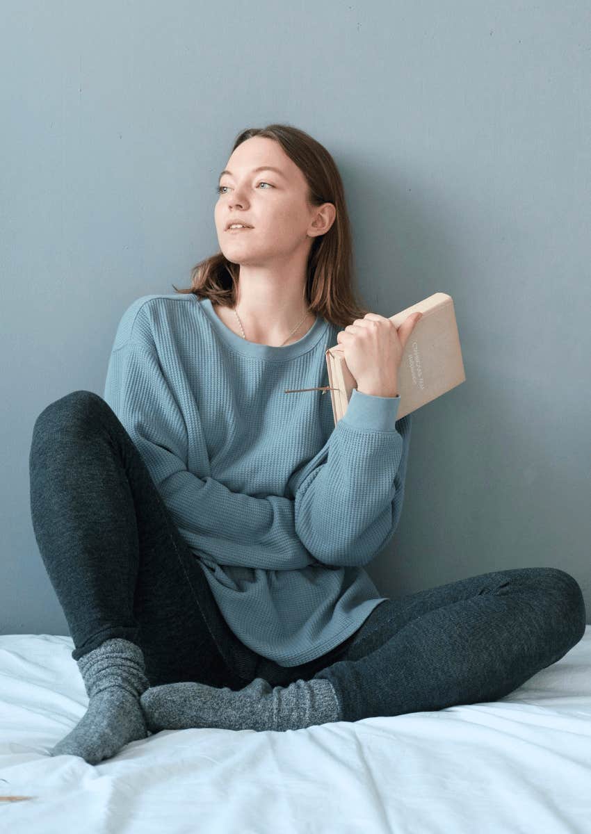 young woman sitting on her bed alone
