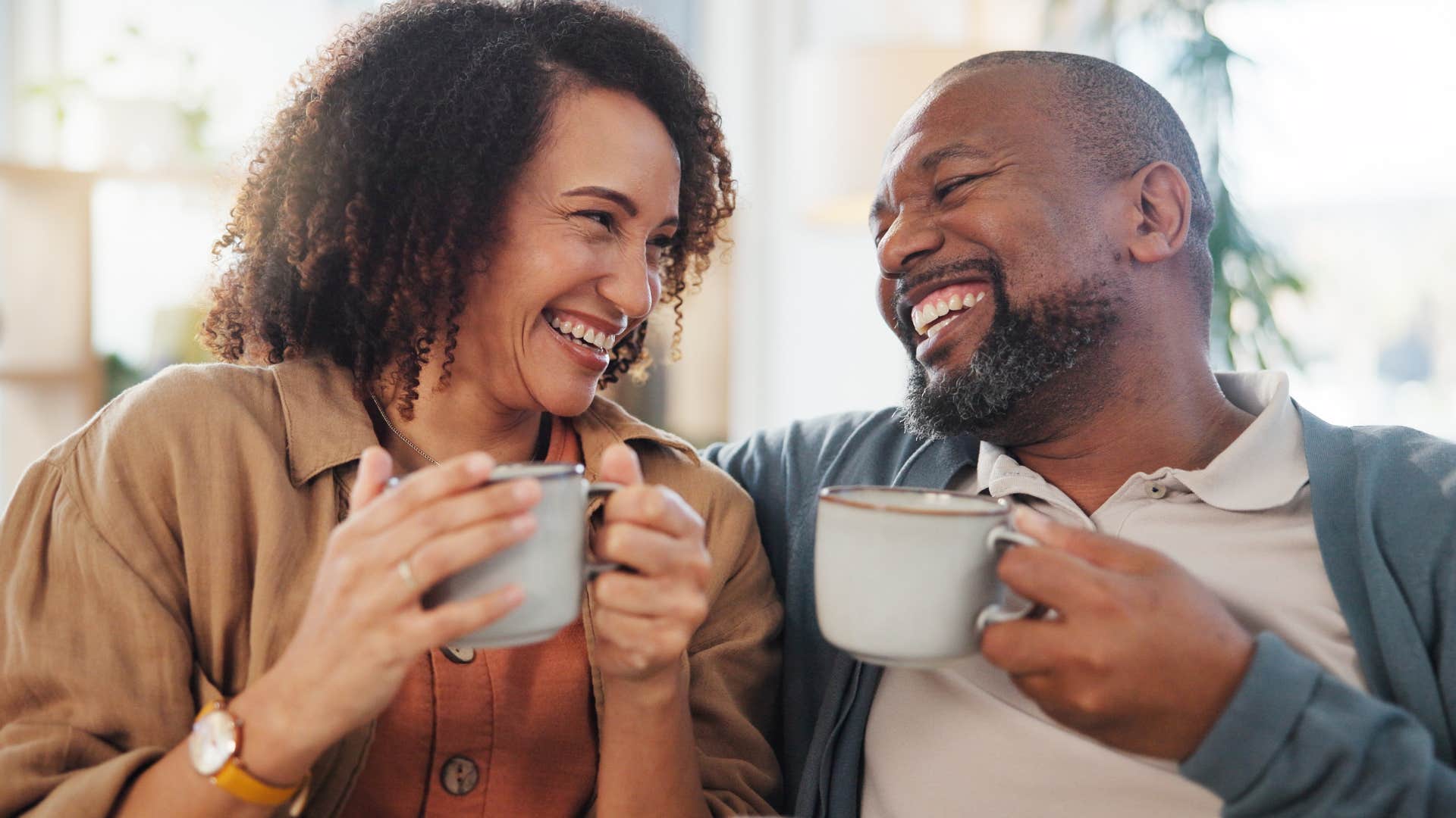 couple who romanticizes the mundane parts of life smiling over coffee