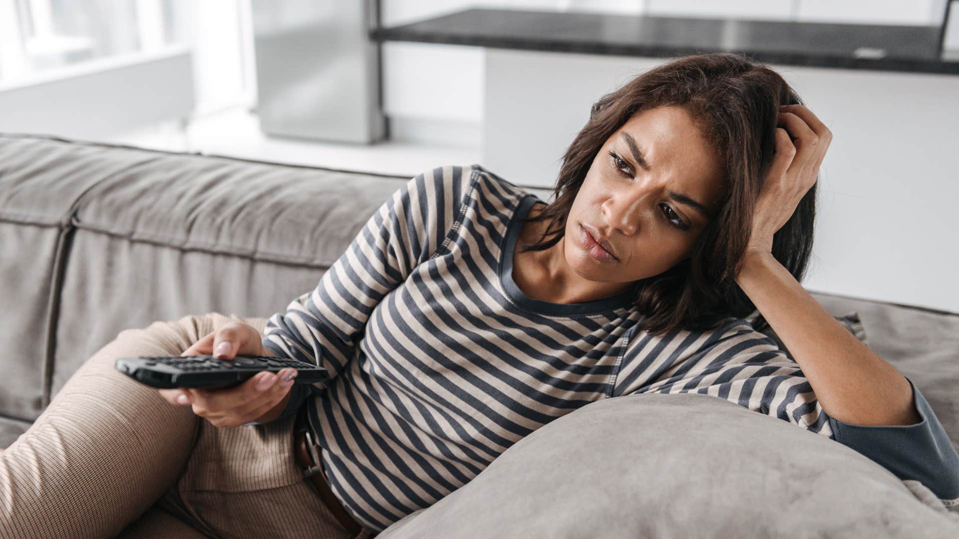 woman on the sofa putting television on as background noise