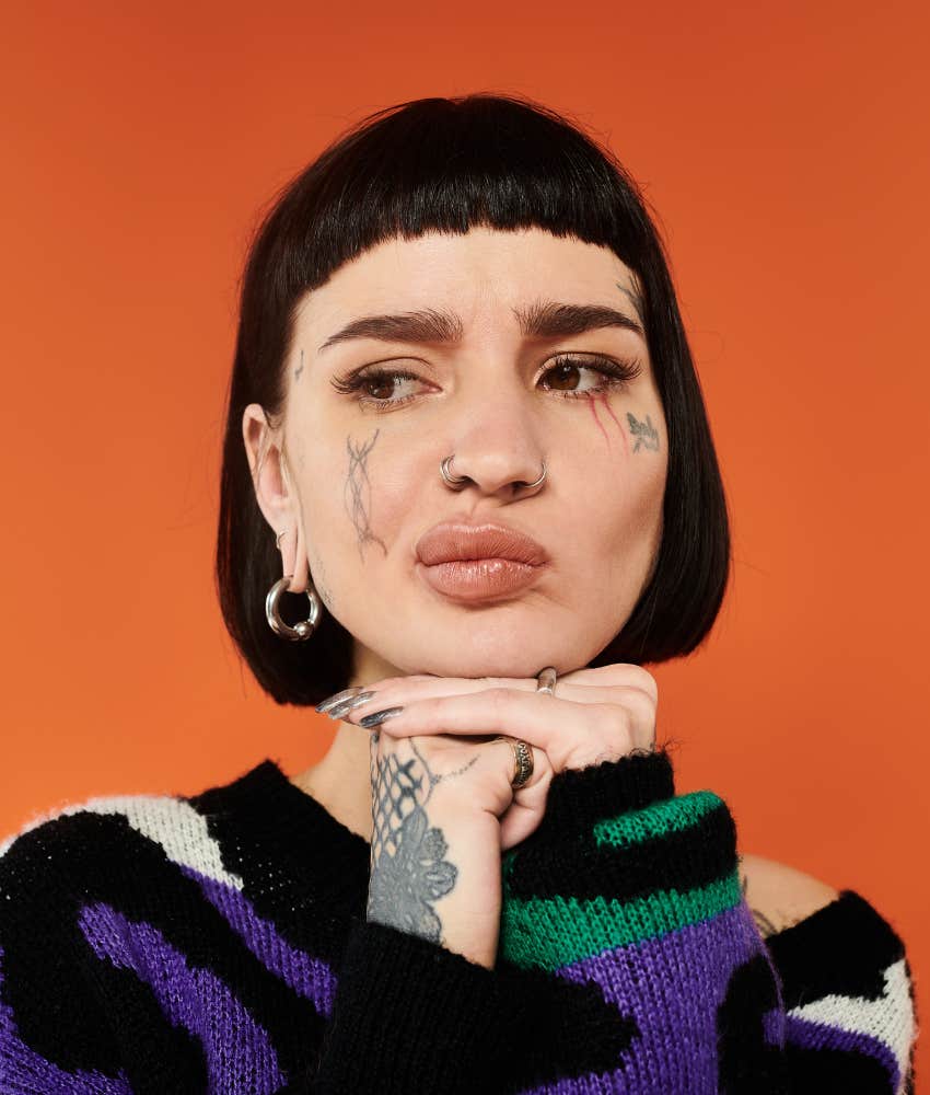 Worried woman with tattoos showing controlling relationship