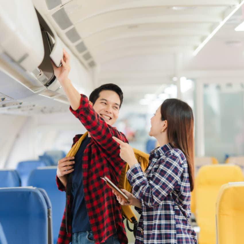 couple blocking walkway on plane while loading luggage
