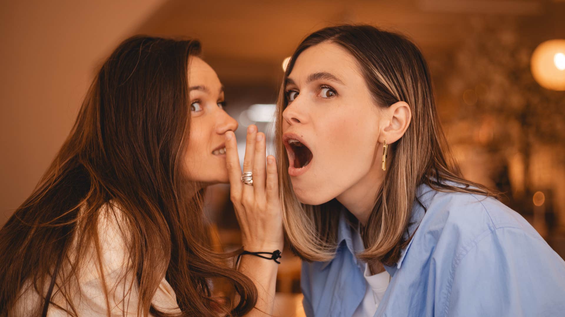 friends whispering in one another's ear 