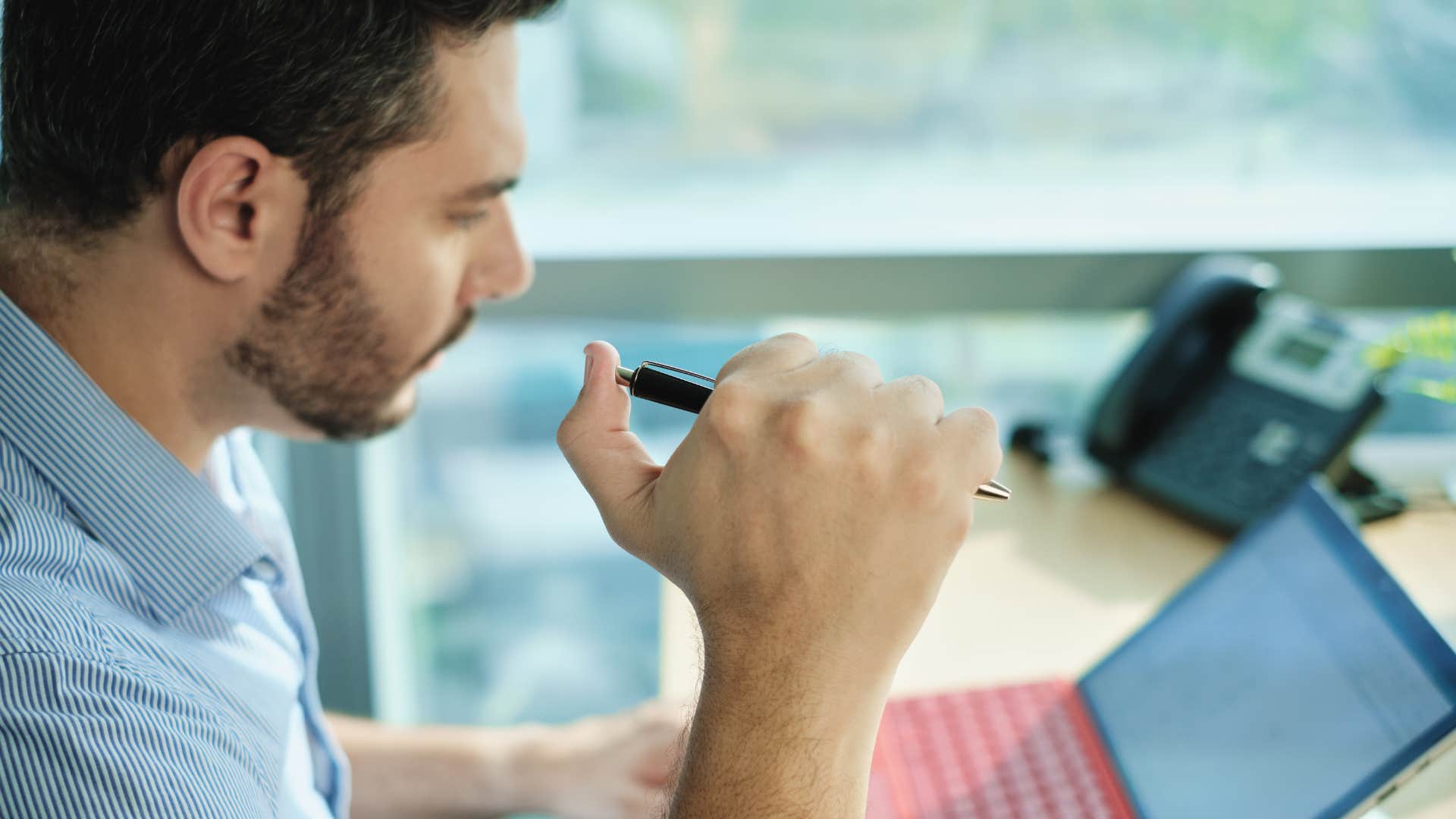 man repetitively clicking his pen at work