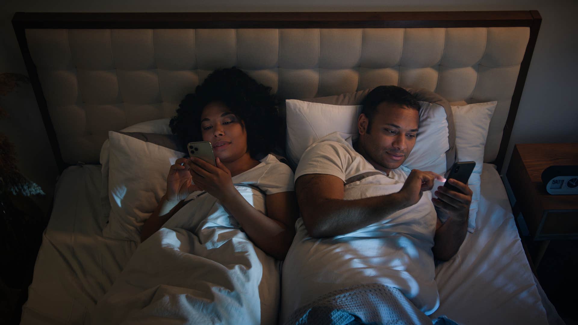 couple on their phones in bed instead of spending quality time together