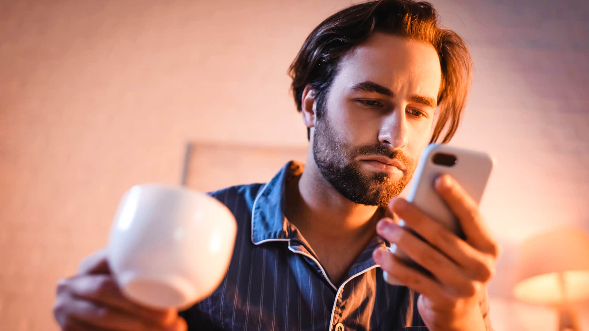 man is on his phone while watching tv because he's uncomfortable with stillness