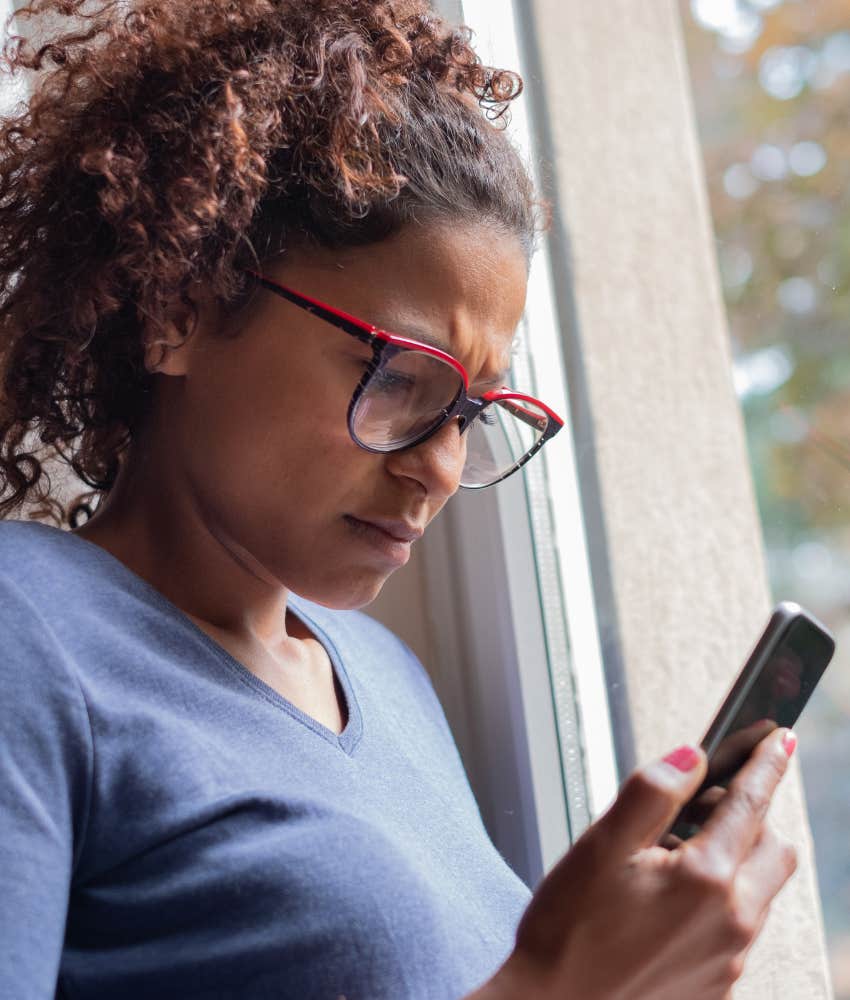 Unhappy person with phone showing they they ex's social media after divorce