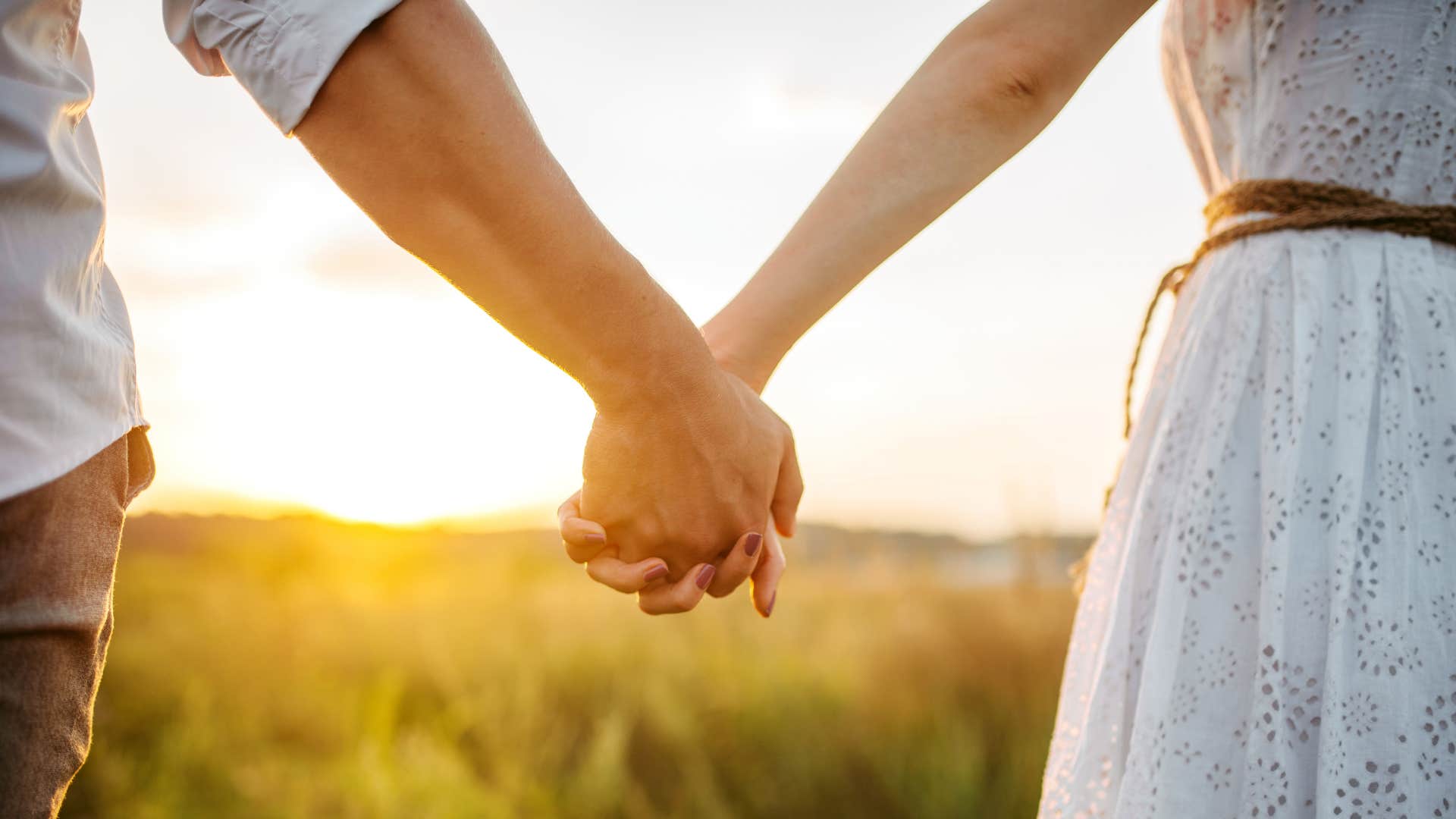 Close couple hold hands walk into sunset showing vulnerability makes relationship happier