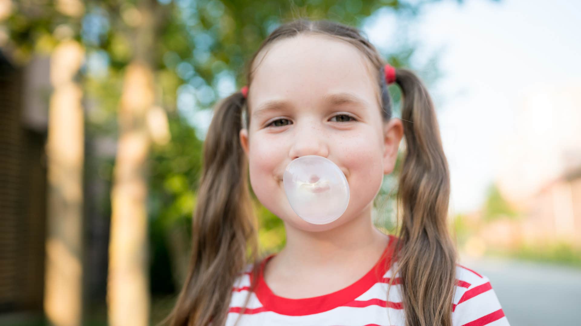 little girl blowing bubble with gum