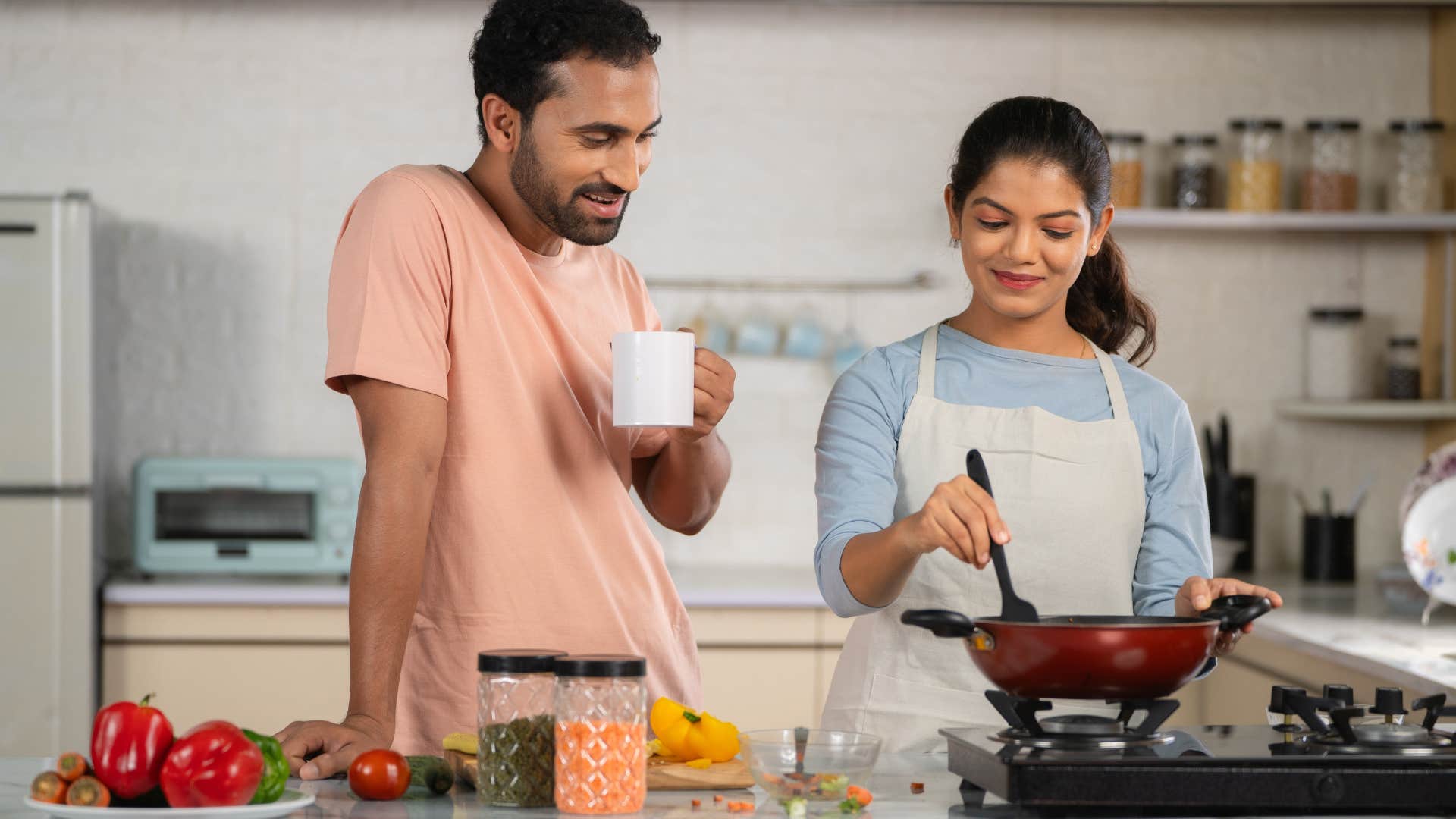 husband with coffee spending time with cooking wife at kitchen