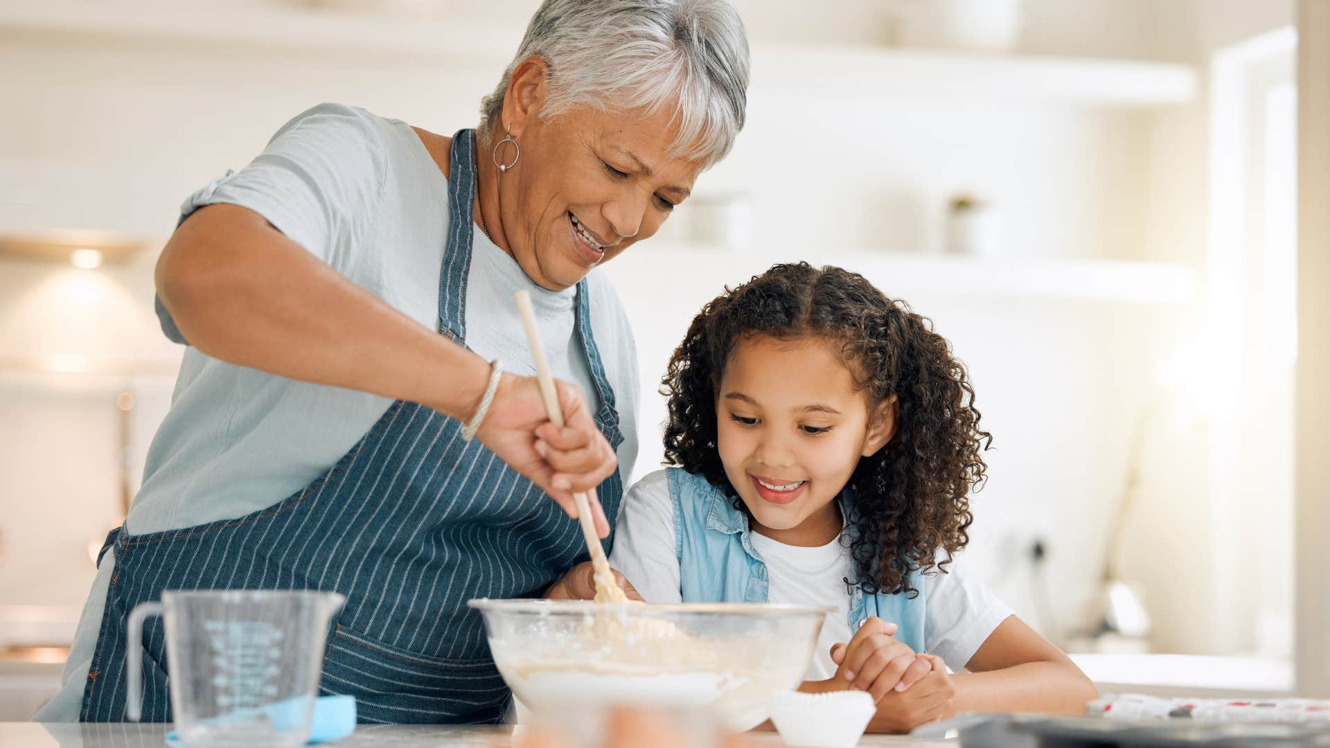 grandmother cooking with granddaughter in kitchen