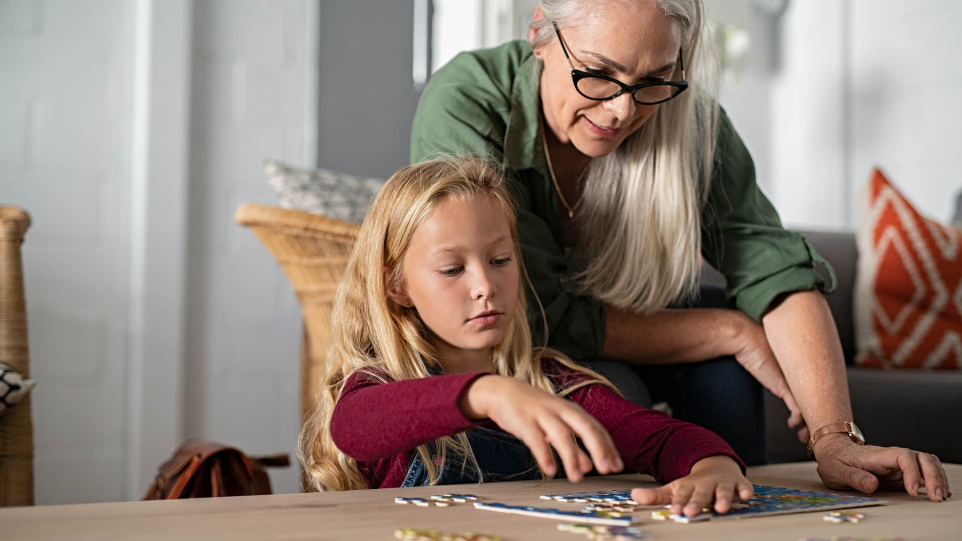 grandma helping granddaughter with puzzle at the table