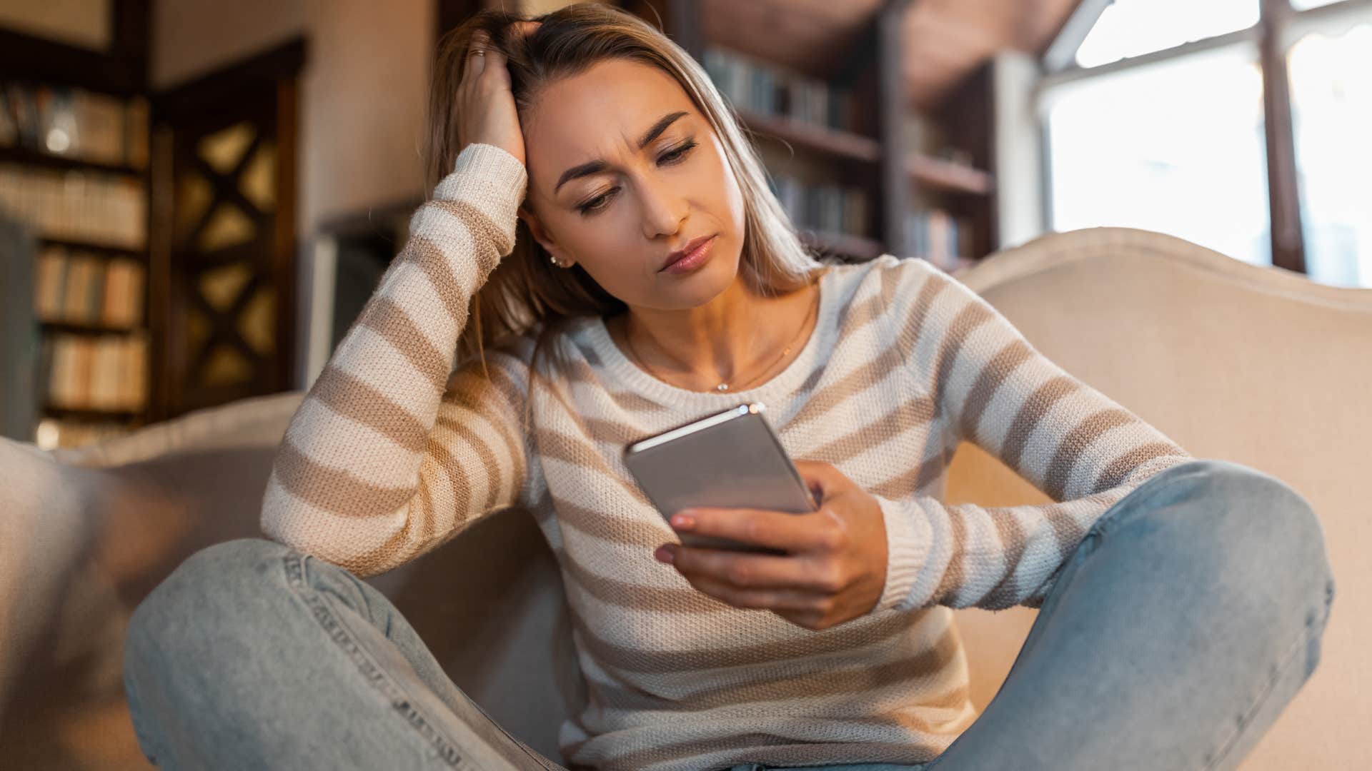 sad woman looking at phone assuming she's not invited to everything