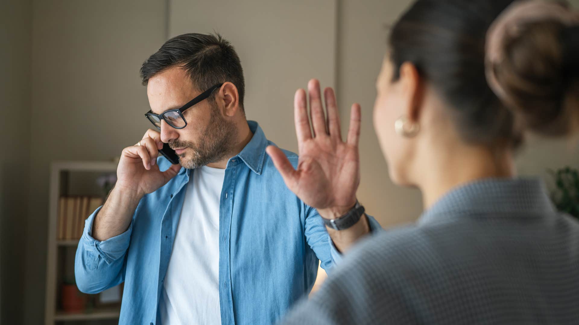 Disrespectful person using phone as excuse puts up hand to partner