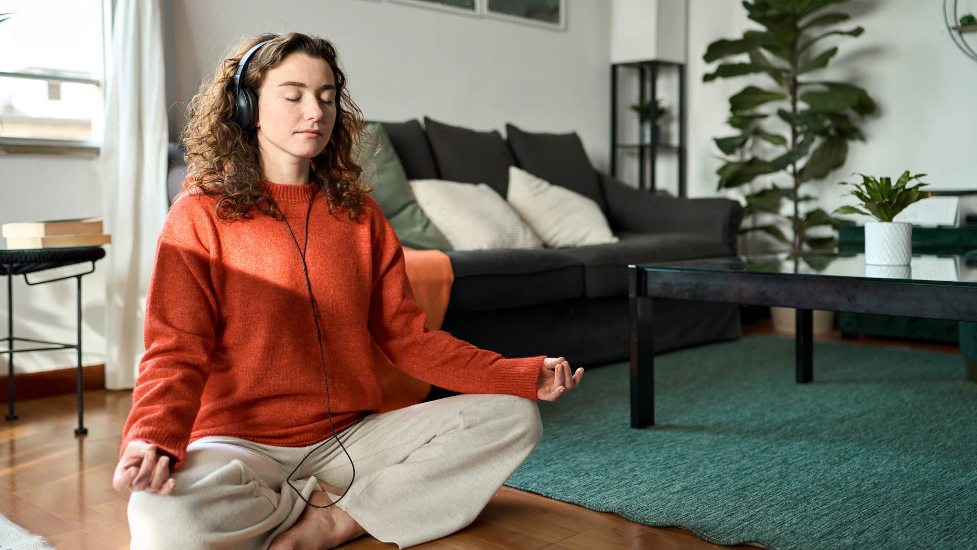 smart woman sitting on floor with headphones meditating