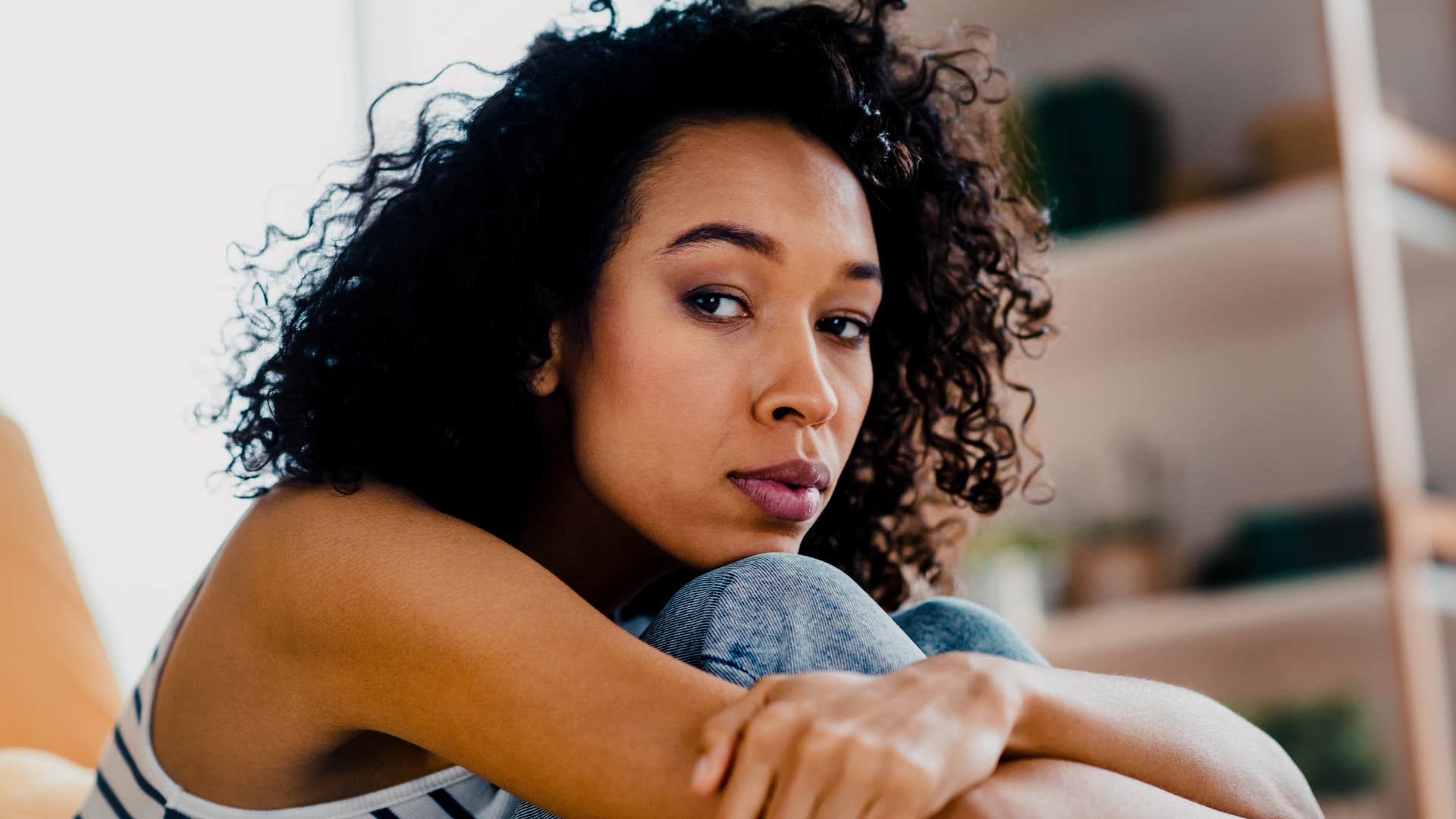 Sad woman hugs legs to chest showing grief stage