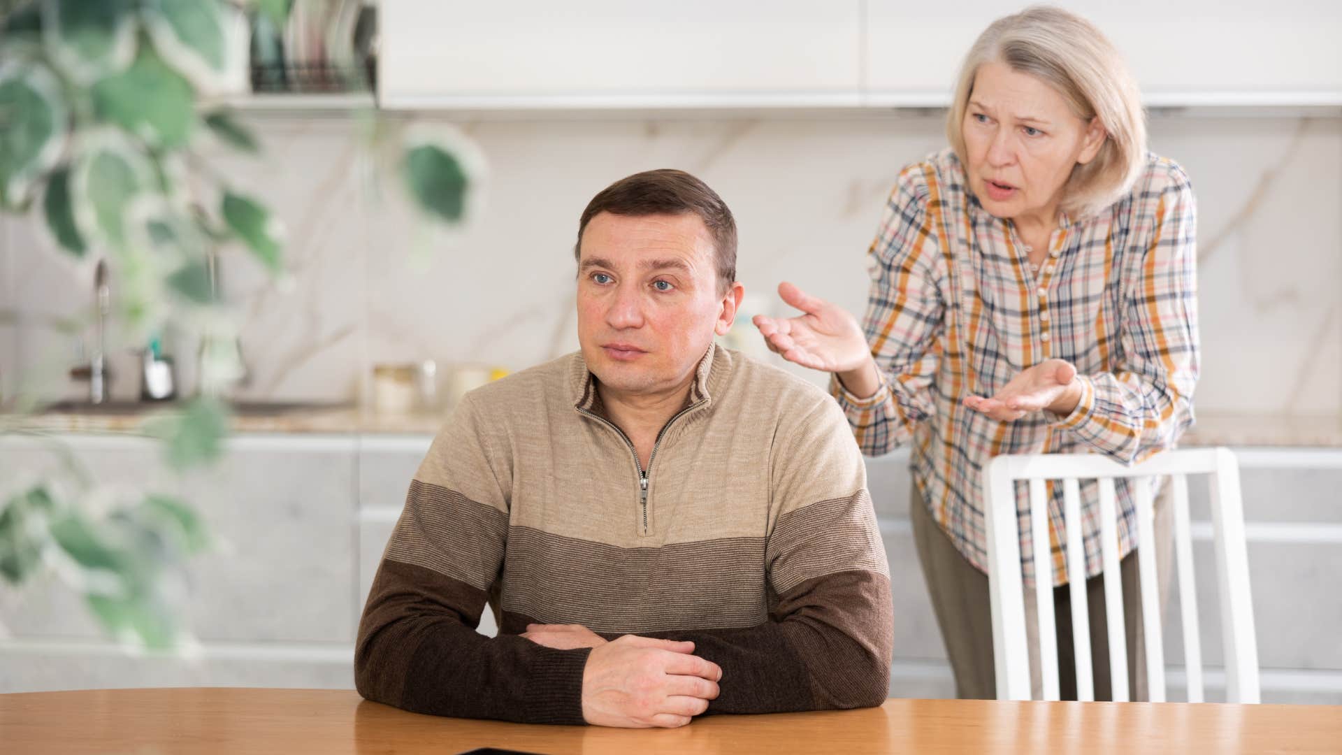 stubborn man saying it's not my fault to his mother confronting him