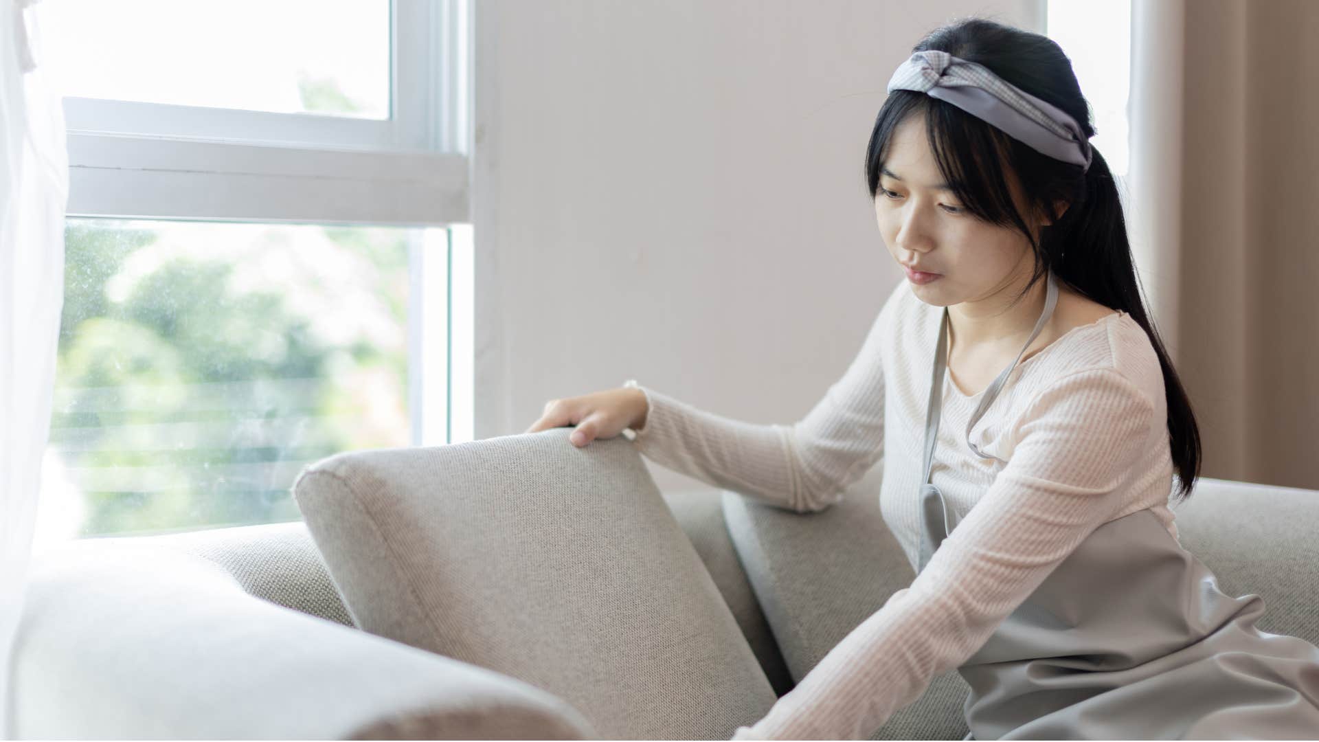 female guest in home looking at crumbs under couch cushions
