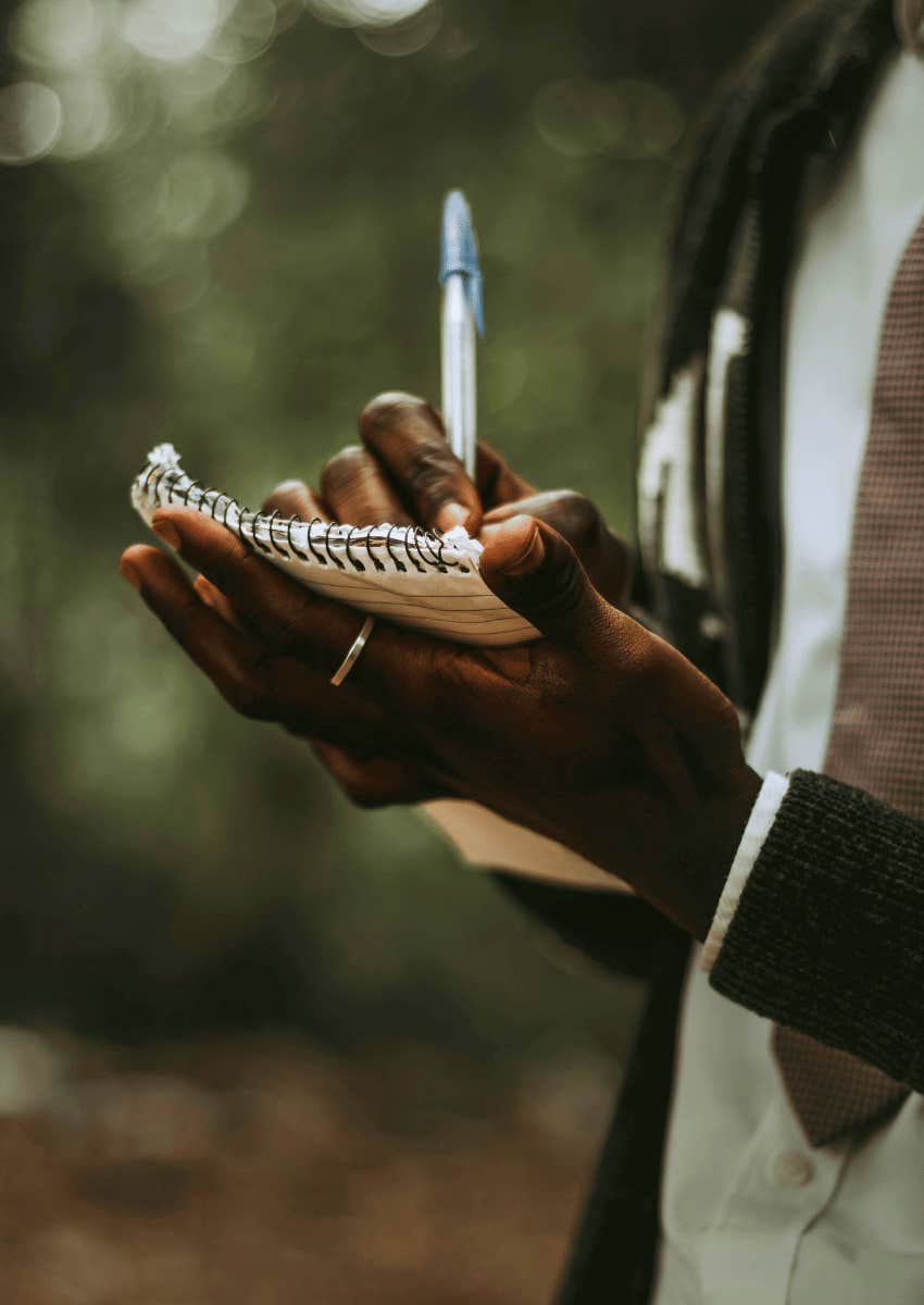man writing in a small notebook