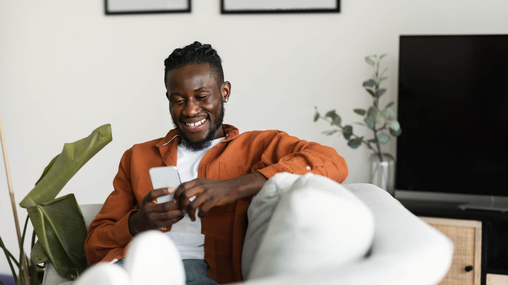 minimalist man sitting in empty living room on his phone