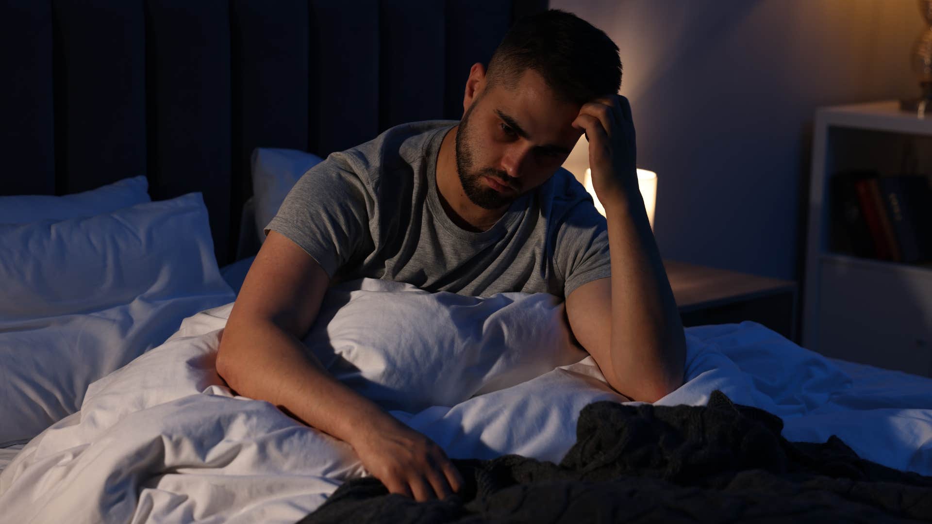 restless man sitting up in his bed at night