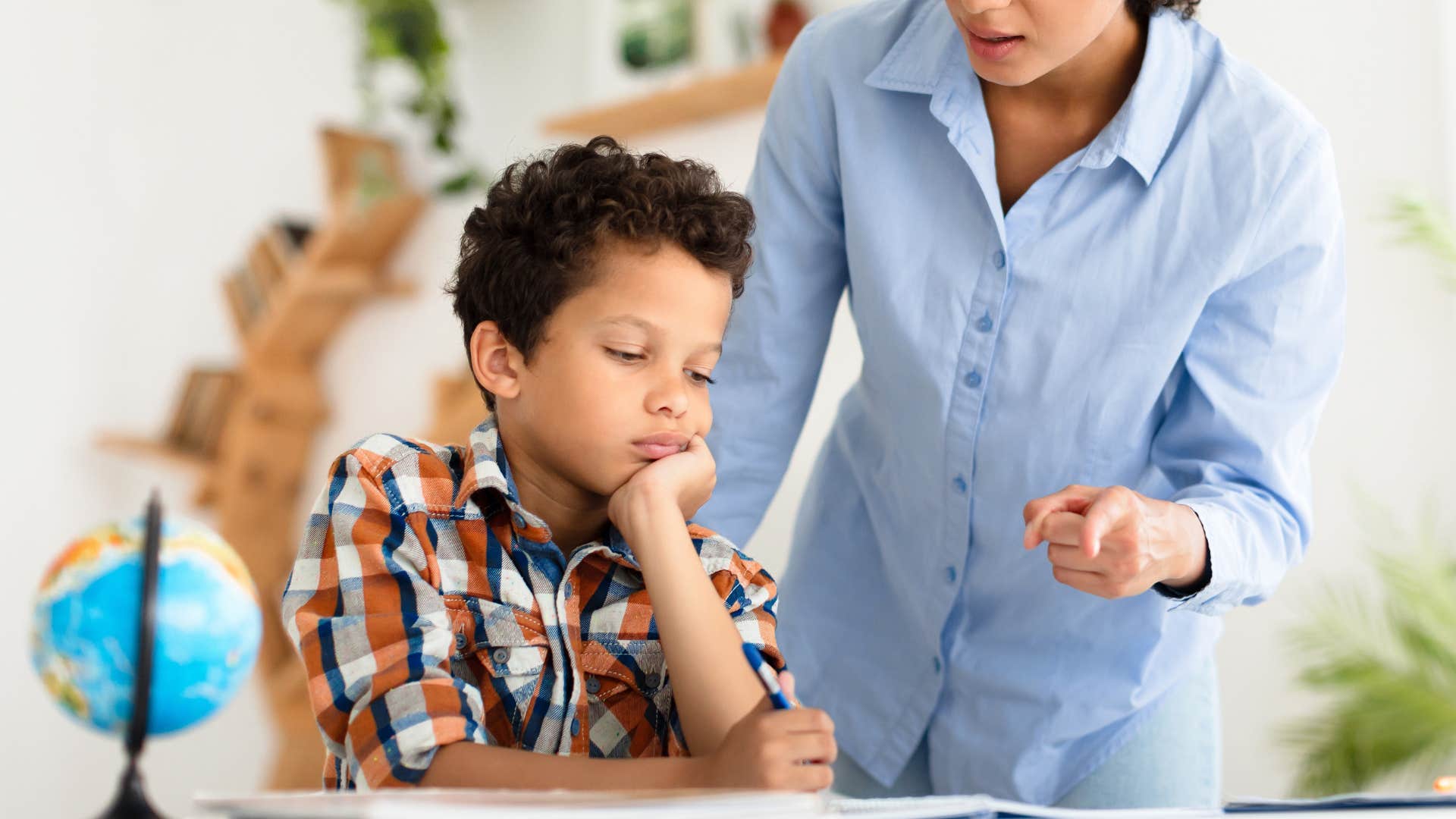 strict mom holding young boy to unrealistic expectations doing schoolwork