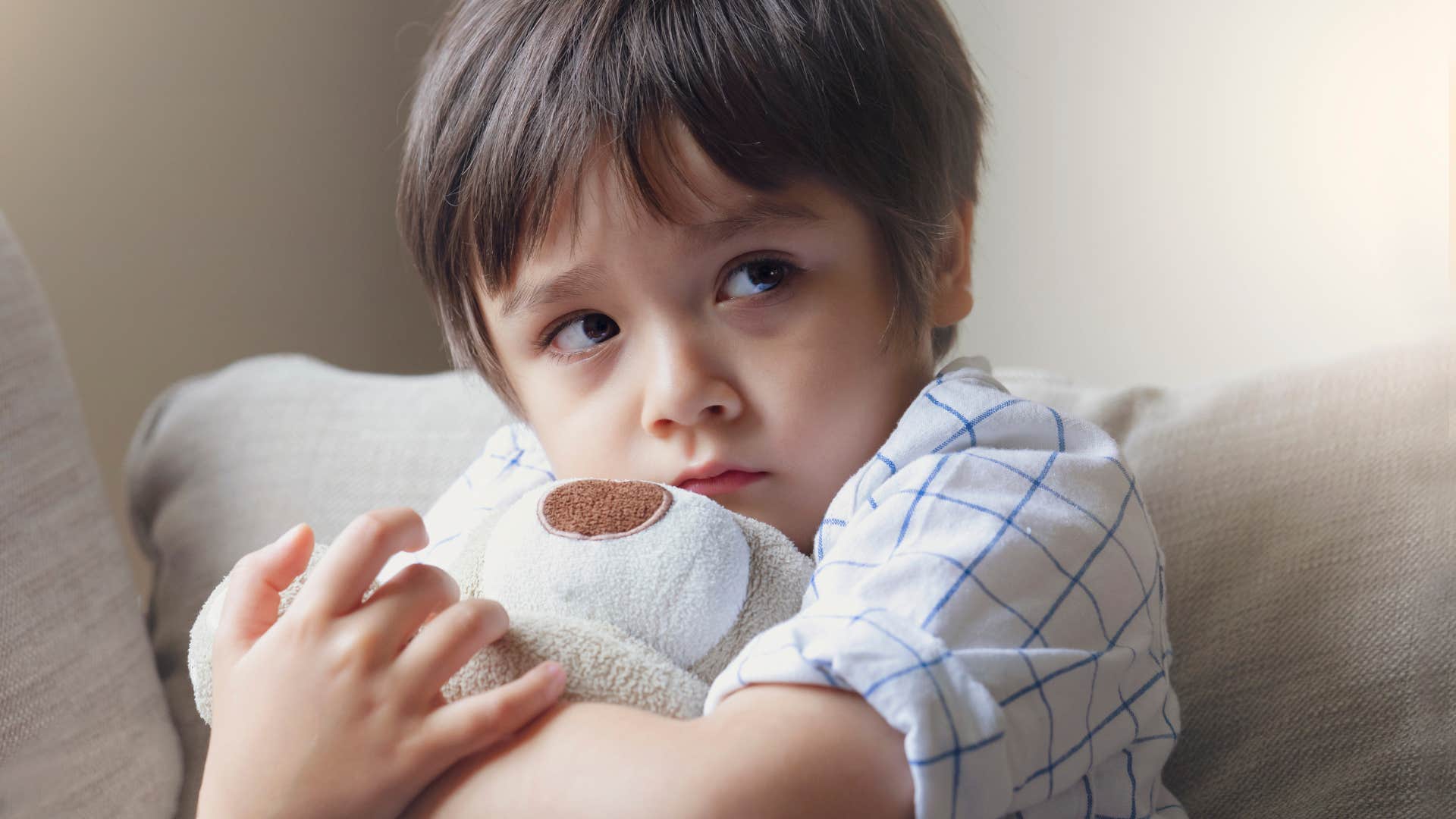 stressed little boy hugging teddy bear growing up in overstimulating home