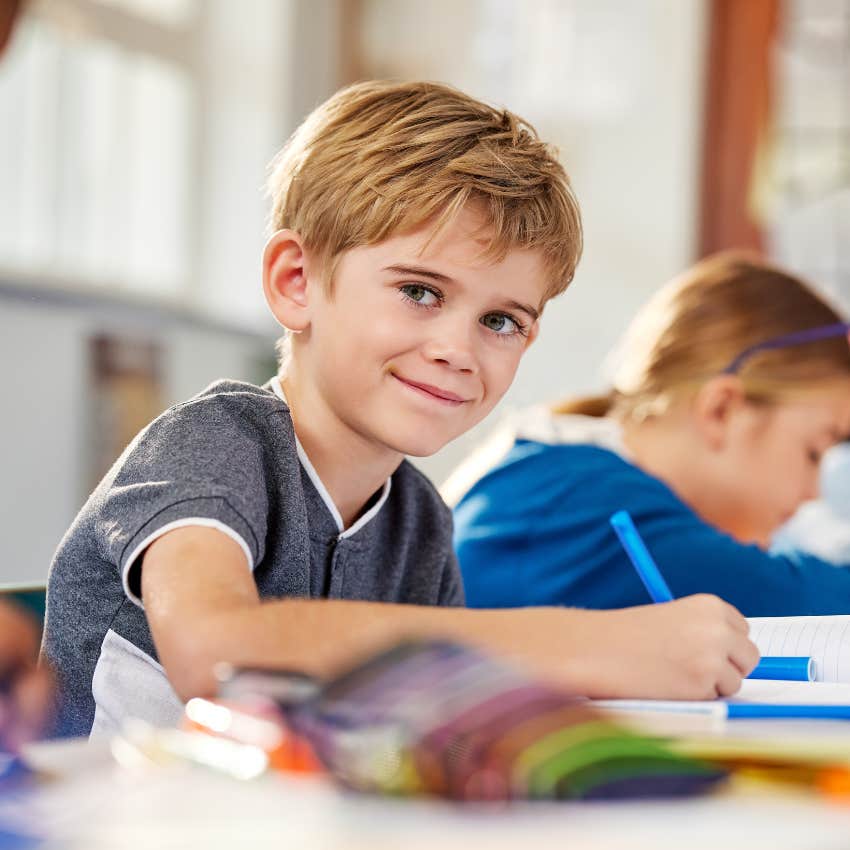 little boy working on assignment at desk in classroom