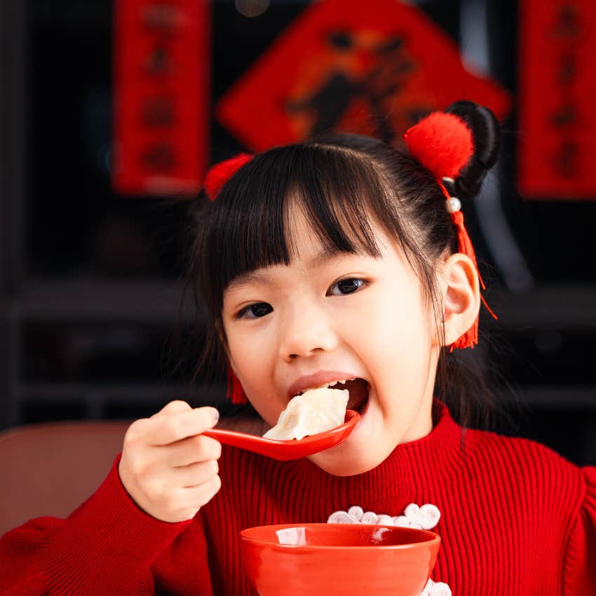 girl eating dumplings night before lunar new year attract good luck