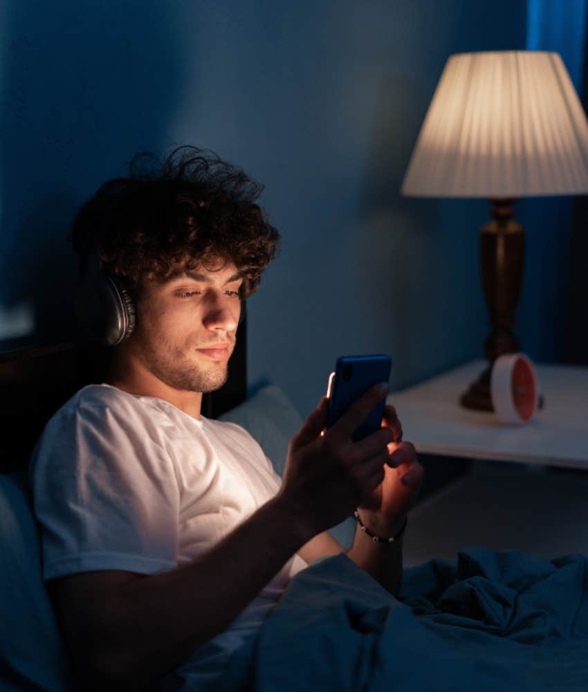 young man staying up late on phone listening to music
