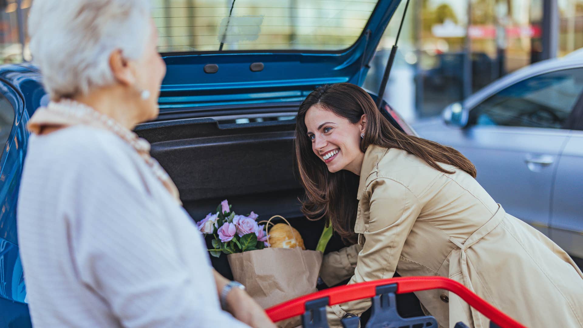 woman helping elderly woman put groceries in her car