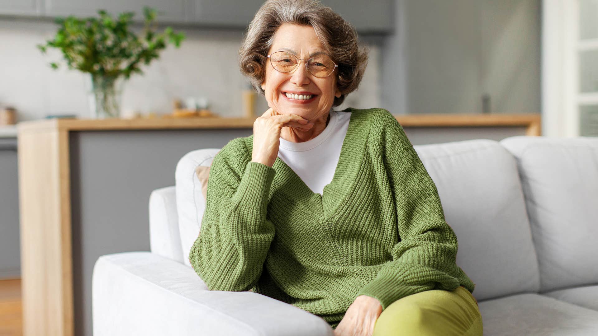 older woman smiling while sitting on couch with plastic cover