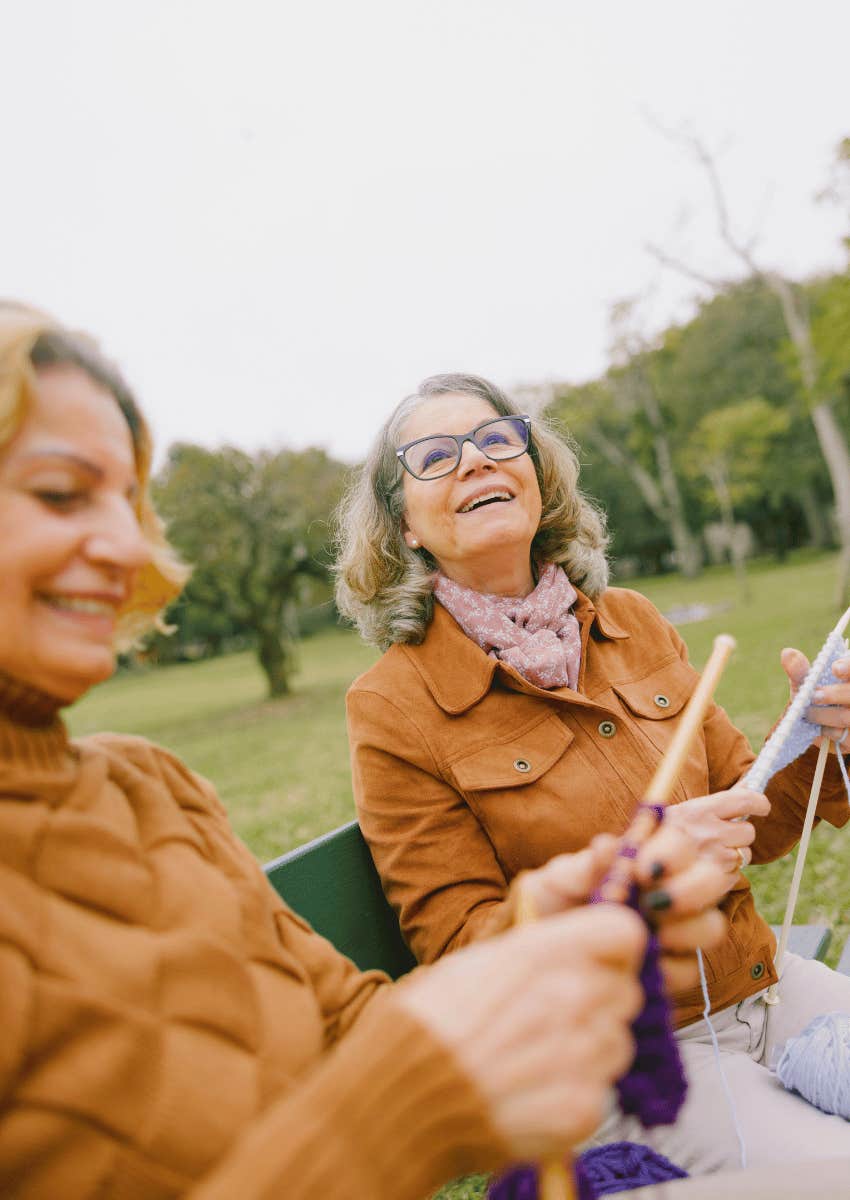 older female couple knitting together outdoors