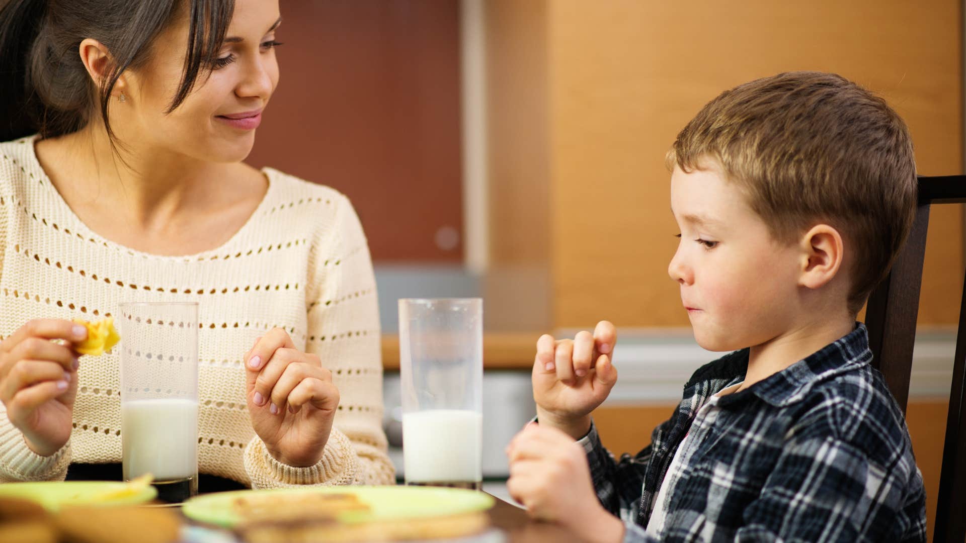 mom telling son eating at the dinner table not to leave until everyone is finished